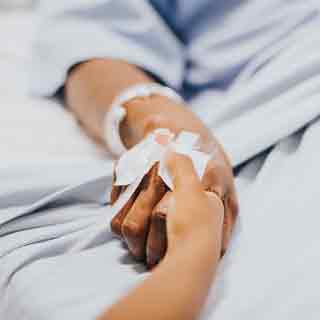 Daughter holding mother's hand in hospital